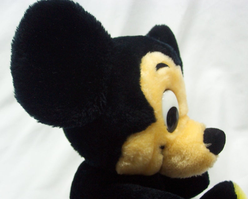 May include: A black and yellow plush Mickey Mouse toy with large black ears and a big smile.