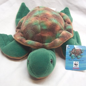May include: Green and brown plush turtle toy with a shell that has a camouflage pattern. The toy has a tag that says "Made exclusively for WWF" and a panda bear logo.