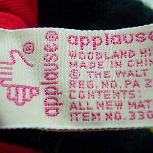 May include: A white tag with pink lettering that reads "applause" and "Woodland Hills, Made in China, The Walt Disney Company, Reg. No. PA 29, Contents: All New Materials, Item No. 3308".