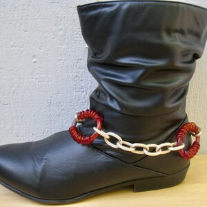May include: Black leather boots with a silver chain and red beaded embellishments around the ankle.
