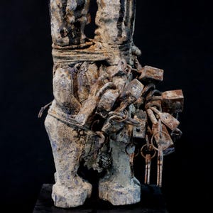 Puede incluir: Escultura desgastada de dos figuras enfrentadas, atadas con cuerdas y cadenas. Las figuras tienen un acabado texturizado y envejecido con acentos oscuros. Una colección de llaves y cerraduras está unida a la escultura.