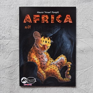 Pode incluir: Uma capa de banda desenhada com fundo preto que apresenta um filhote de guepardo amarelo e laranja enroscado numa caverna escura. O t&iacute;tulo "AFRICA" est&aacute; escrito em letras vermelhas com contorno branco. O texto "Maura "Arvent" Pompili" e "n.01!" tamb&eacute;m s&atilde;o vis&iacute;veis na capa.