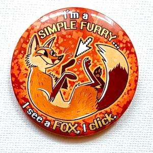 May include: Circular orange button featuring a cartoon fox. The fox is depicted lying down with a computer cursor hovering over its paw. Text on the button says "I'm a SIMPLE FURRY... I see a FOX, I click."
