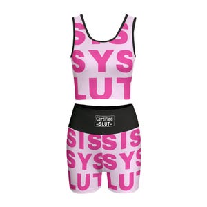 Könnte beinhalten: Ein zweiteiliges Sport-Set in Rosa, bestehend aus einem Crop-Top und Shorts. Das Set ist mit dem Wort "SYS LUT" in fetter, rosa Schrift bedruckt. Die Shorts haben einen schwarzen Bund mit dem Text "Certified «SLUT»".