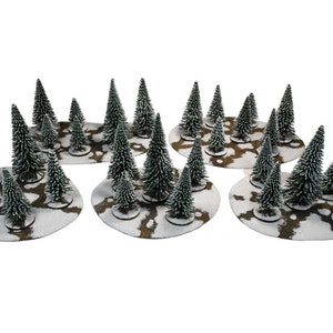 May include: Six snowy forest bases with miniature evergreen trees. Each base is a brown and white oval with a snowy surface and a few brown patches. The trees are green with white tips.