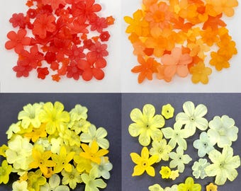 May include: Assortment of colorful plastic flower embellishments in red, orange, yellow, and light yellow. The flowers are in various sizes and shapes.