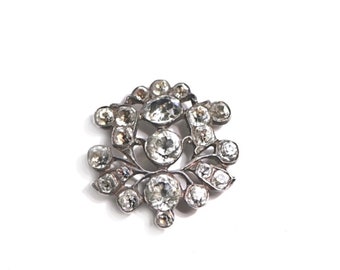 May include: A silver brooch with a cluster of clear rhinestones set in a floral design.