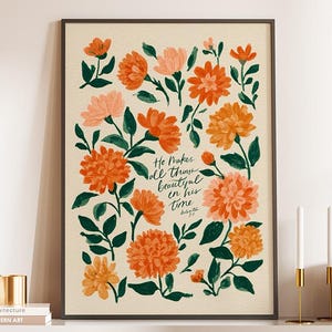 May include: A framed floral art print with orange and peach flowers and green leaves. The print includes the text "He makes all things beautiful in his time." The artwork is displayed on a white cabinet.