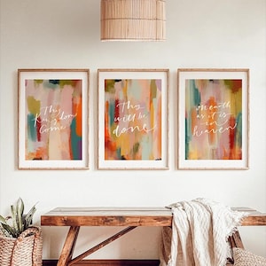 Puede incluir: Tres impresiones artísticas enmarcadas con diseños abstractos de pinceladas en tonos naranja, rosa, verde y morado. Cada impresión presenta texto en cursiva blanca. Las impresiones se muestran encima de un banco de madera con una cesta tejida.