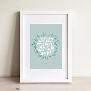 May include: A framed print with a teal green background and white text that reads "I have come that they may have life and have it to the full" with a teal green floral wreath around the text. The bottom of the print reads "John 10:10".