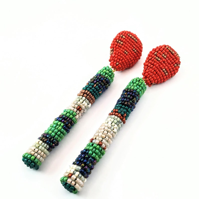 May include: A pair of long, beaded earrings with a red teardrop-shaped bead at the top and a multi-colored beaded design in shades of green, white, and blue.