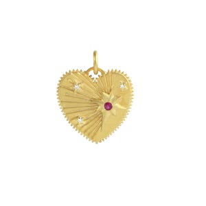 Puede incluir: Colgante dorado en forma de corazón con diseño de estrella. El colgante presenta una estrella central con una gema roja y tres estrellas más pequeñas con gemas claras. Los bordes tienen un diseño dentado.