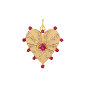 May include: A gold heart-shaped pendant with a red ruby in the center and surrounded by smaller diamonds. The pendant has a sunburst design with rays of diamonds radiating from the center.