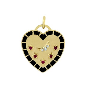 Puede incluir: Un colgante de corazón de oro con esmalte negro y piedras de rubí rojo. El colgante presenta una luna creciente con un diamante y cinco estrellas.