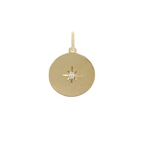 Puede incluir: Colgante dorado con dise&ntilde;o circular. Presenta un dise&ntilde;o de estrella con una peque&ntilde;a gema redonda y transparente en el centro. Tiene un peque&ntilde;o lazo en la parte superior para una cadena.