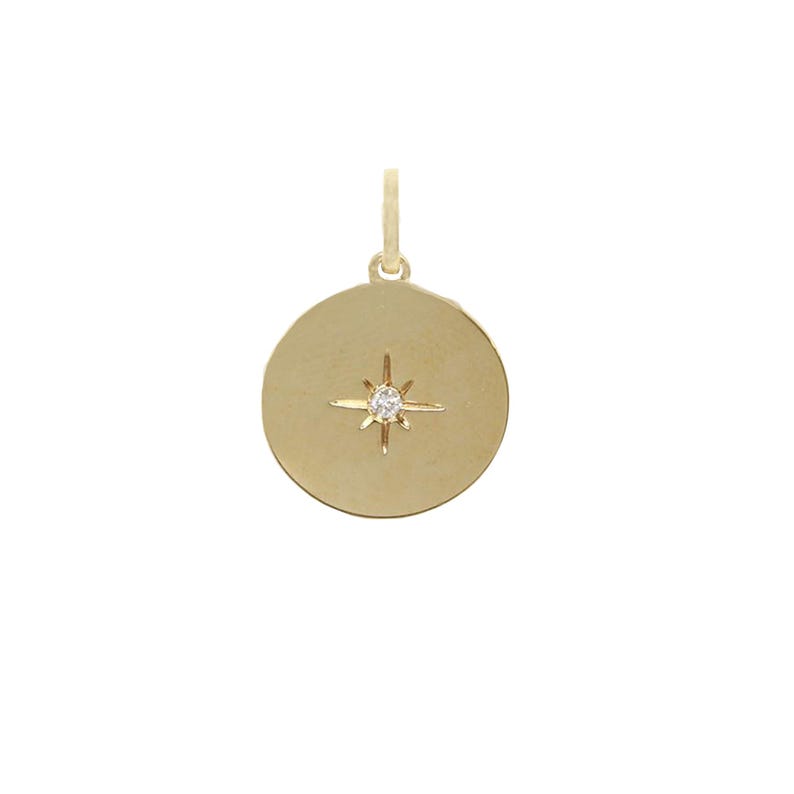 Puede incluir: Colgante dorado con dise&ntilde;o circular. Presenta un dise&ntilde;o de estrella con una peque&ntilde;a gema redonda y transparente en el centro. Tiene un peque&ntilde;o lazo en la parte superior para una cadena.