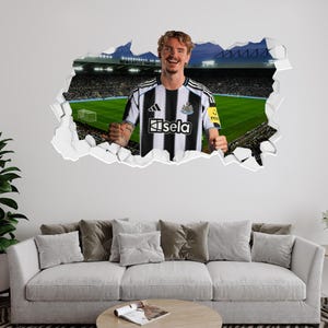 Puede incluir: Un adhesivo de pared que representa a un jugador de f&uacute;tbol con una camiseta a rayas blancas y negras con la palabra "isela". El fondo muestra un estadio con las palabras "Newcastle United". El jugador sonr&iacute;e y parece estar celebrando.