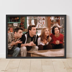 May include: A framed print of the "Friends" TV show cast. Four actors are depicted looking upwards with expressions of surprise. The show's logo is visible in the top right corner. The frame is black.