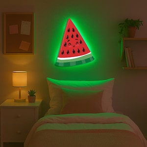 May include: A watermelon-shaped wall light with a smiling face and black seeds. The light has a red centre, white rind, and green stripes, with a bright green neon glow around the edges. The light is mounted on a green wall above a bed.