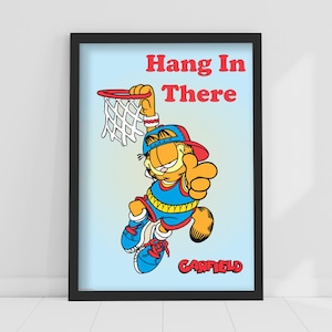 Peut inclure: Impression encadrée de Garfield en uniforme de basket-ball, en train de dunker un ballon. Les mots "Hang In There" sont au-dessus de Garfield, et "Garfield" est en dessous. Le fond est un dégradé bleu clair.