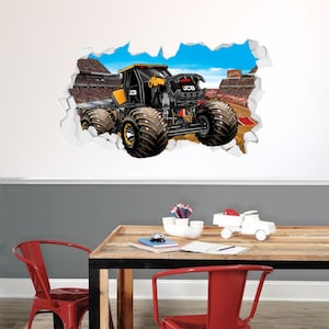 May include: A yellow and black monster truck with the word "JCB" on the side, breaking through a wall with a stadium in the background.