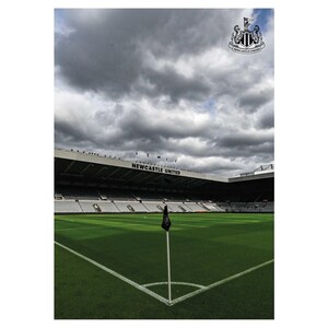 May include: A view of a soccer field with a black flag in the corner. The stands of the stadium are visible in the background. The sign above the stands reads "NEWCASTLE UNITED".