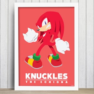 May include: A framed poster of Knuckles the Echidna, a red character from Sonic the Hedgehog, against a red backdrop. The poster displays the character's name in white capital letters. The image is in a white frame.