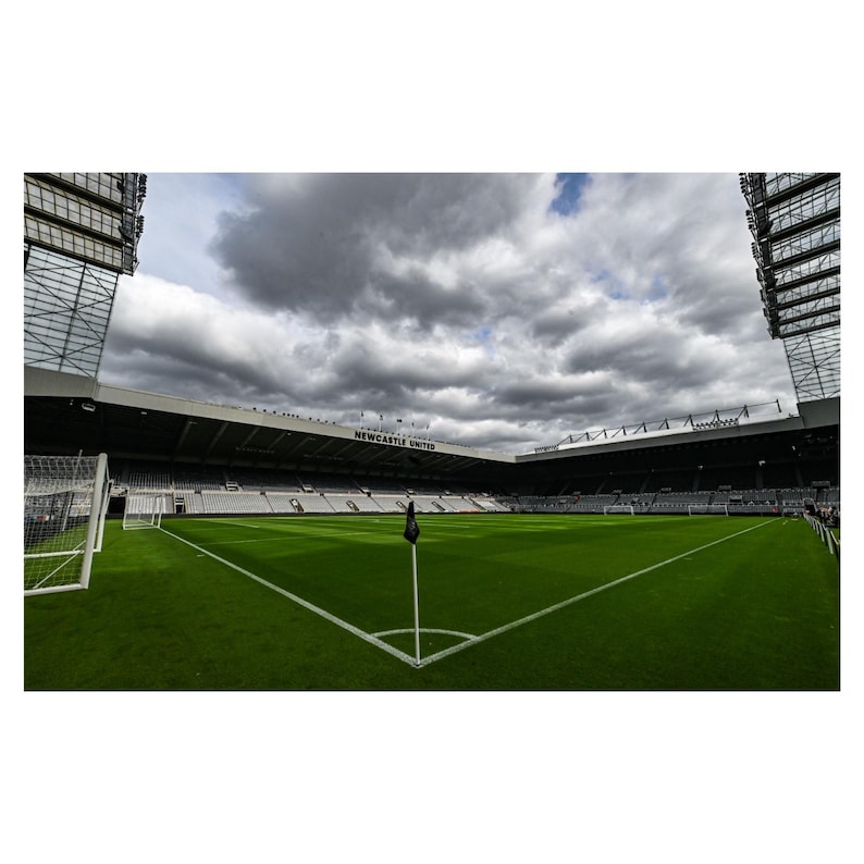 Puede incluir: Un campo de f&uacute;tbol vac&iacute;o con una bandera negra en el centro. El campo est&aacute; rodeado por un gran estadio con asientos negros y un letrero que dice "NEWCASTLE UNITED".