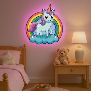 May include: A whimsical unicorn night light with a rainbow and cloud design. The light features a cartoon unicorn with a golden horn, standing on a blue cloud in front of a rainbow. The light has a pink border and is mounted on a wall.