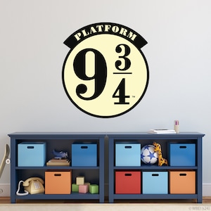 Peut inclure: Une étagère bleue à deux niveaux, chaque niveau comportant six bacs de rangement. L'étagère supérieure a un bac bleu, un bac bleu clair et un bac bleu. L'étagère inférieure a un bac rouge, un bac bleu clair et un bac orange. L'étagère est contre un mur blanc avec un autocollant circulaire noir et jaune qui dit "Platform 9 3/4" dessus.