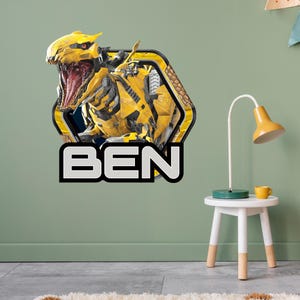 May include: A yellow and black robot-like creature with an open mouth, set within a hexagonal frame. The name "BEN" is displayed in bold, white letters with a black outline. The image is likely a wall decal.