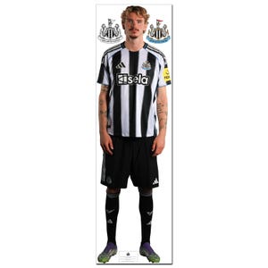 May include: A person wearing a black and white striped football shirt with the word "Sela" on the front, black shorts, and black socks. The shirt has the Newcastle United logo. The person is wearing green and purple football boots.