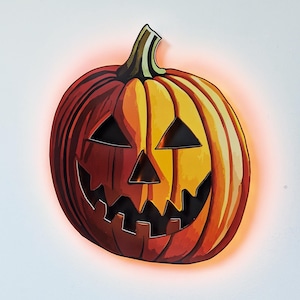May include: A carved orange and yellow jack-o'-lantern pumpkin with a black smiling face. The pumpkin is lit from behind, creating a warm glow.