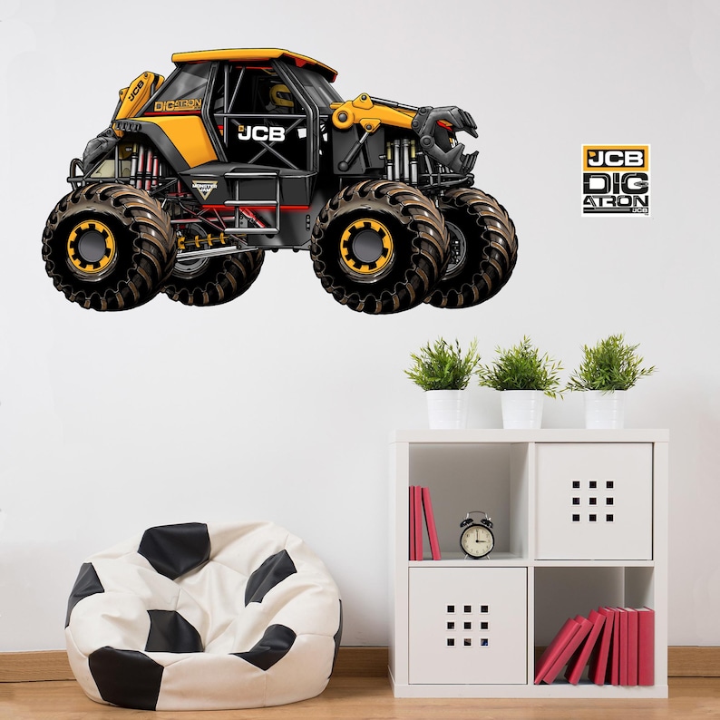Op de afbeelding: Een zwarte en gele monster truck muursticker met de tekst "JCB" en "DIG ATRON". De truck heeft oversized banden en een gedetailleerd ontwerp. Op een witte muur, met een zitzak en een plank met planten.
