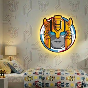 Könnte beinhalten: Eine beleuchtete Wanddekoration mit einem Cartoon-Robotergesicht in Gelb, Orange und Grau, das vor einem blauen und roten Kreis angeordnet ist. Die Wand ist mit Robotersymbolen und Leiterplattenmustern verziert. Das Bett hat eine passende Bettdecke und Kissen im Roboter-Design.