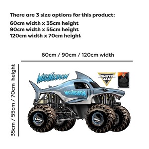 Op de afbeelding: Een lichtblauwe en grijze Megalodon monstertruck afbeelding met de tekst "Megalodon". De afbeelding bevat maatopties: 60 cm x 35 cm, 90 cm x 55 cm en 120 cm x 70 cm. Het Monster Jam logo is ook zichtbaar.