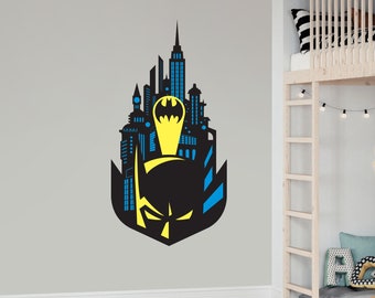 May include: Black and yellow Batman silhouette with a cityscape behind it. The silhouette is on a gray wall.