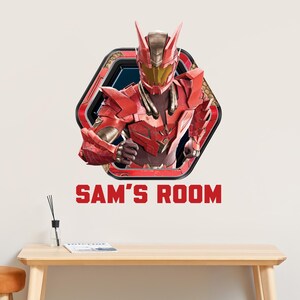 May include: A red superhero figure in a hexagonal frame with the text "SAM'S ROOM" in red. The superhero is wearing a red and gold helmet and armor. The image is a wall decal.