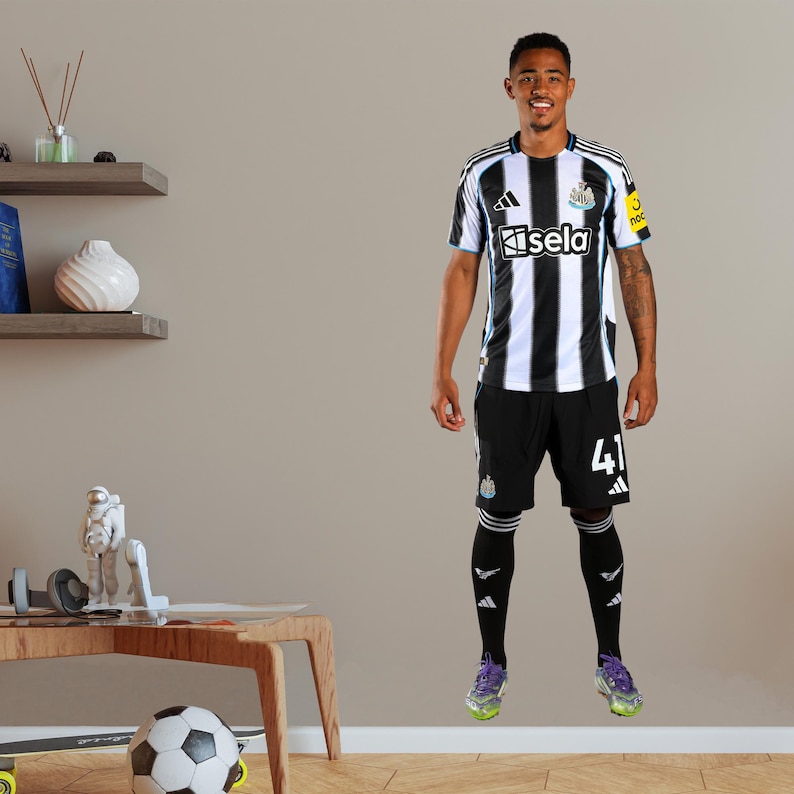 May include: A person wearing a black and white striped soccer jersey with the word "Kisela" on the front. The person is also wearing black shorts with the number "41" on the leg, black socks, and purple sneakers. The jersey has a black collar and white stripes.