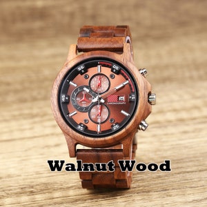 May include: A brown wooden wristwatch with a chronograph face. The watch has a red second hand and a date window that reads "26". The watch face also has the word "CHRONOGRAPH" printed on it. The watch band is made of wood and has a walnut wood finish.
