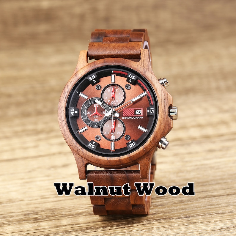 May include: A brown wooden wristwatch with a chronograph face. The watch has a red second hand and a date window that reads "26". The watch face also has the word "CHRONOGRAPH" printed on it. The watch band is made of wood and has a walnut wood finish.
