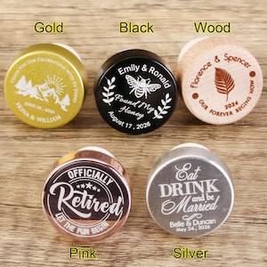 May include: Ten different bottle stoppers with various designs and colors. The stoppers are made of wood, metal, and plastic. The designs include a bee, a leaf, a mountain range, a retirement message, and a wedding message.