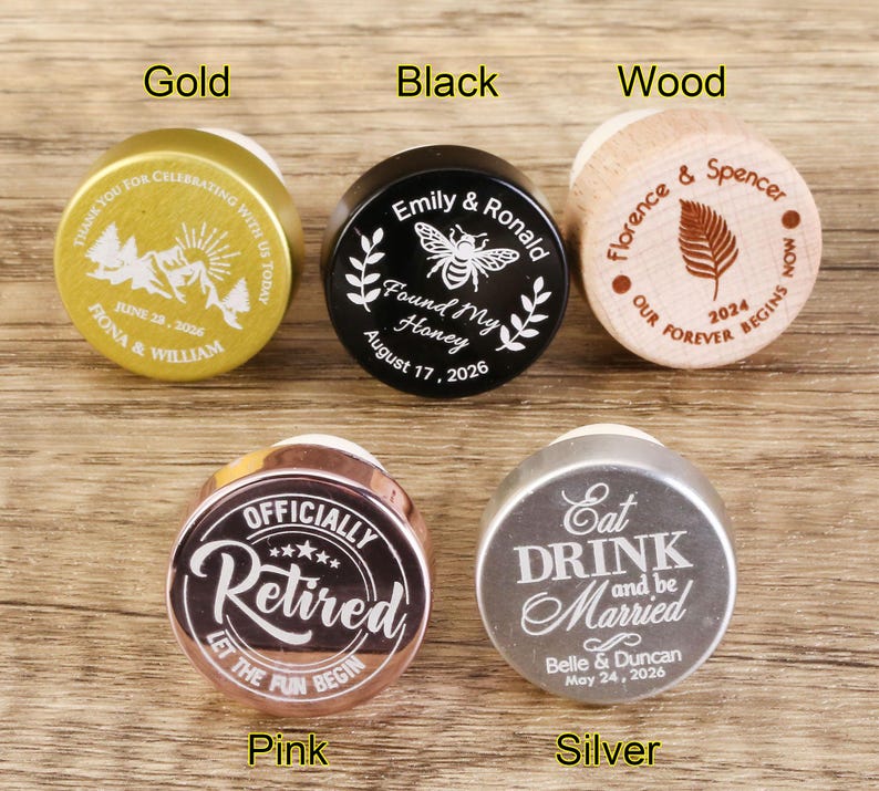 May include: Ten different bottle stoppers with various designs and colors. The stoppers are made of wood, metal, and plastic. The designs include a bee, a leaf, a mountain range, a retirement message, and a wedding message.
