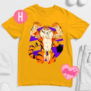 Può includere: T-shirt giallo senape con un personaggio di tigre muscoloso a strisce arancioni e nere, che flette le braccia. La tigre è ambientata su una forma geometrica viola. Un cuore rosa con la scritta "Gold" è visibile.