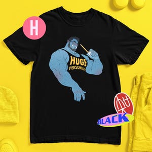 Könnte beinhalten: Ein schwarzes T-Shirt mit einer Grafik eines muskulösen blauen Charakters mit Bart und Brille, der ein schwarzes Tanktop mit dem gelben Text "HUGE PERSONALITY" trägt und ein Getränk mit einem Strohhalm hält. Das Motiv ist mittig platziert.