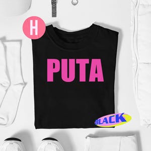 May include: Black t-shirt with the word "PUTA" in large, bright pink letters. The shirt is surrounded by white accessories, including a hat, socks, and sneakers. A pink circle with the letter "H" is visible.