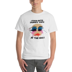 May include: White t-shirt with a black and white graphic print of a woman's face with colorful makeup and the text "I ran into Tammy Faye at the mall".