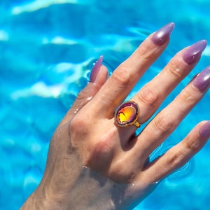 Small oval shape gold waterproof mood ring worn on hand in water from a swimming pool