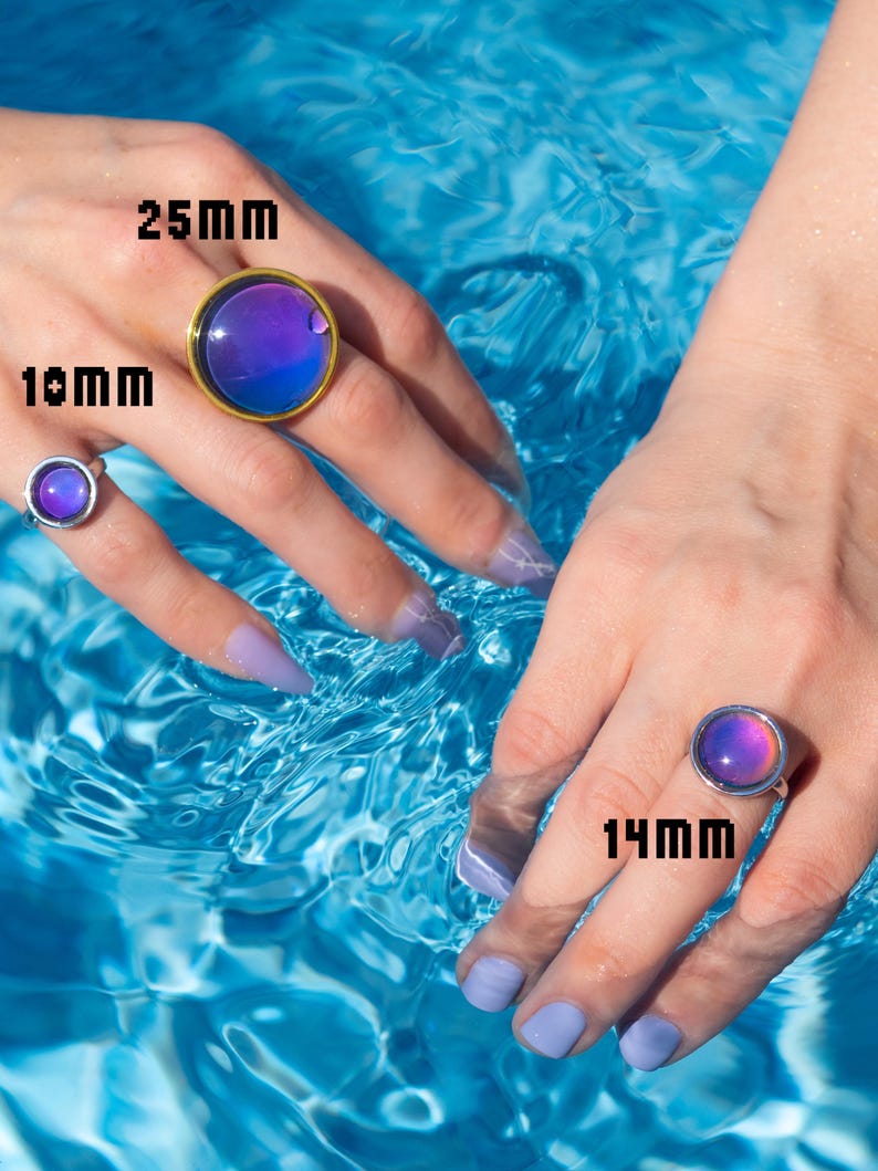 Round mood rings of three sizes small medium and large on hands in swimming pool, gold and silver rings in blue and purple tones