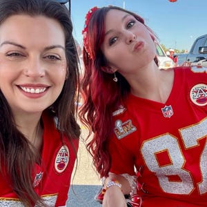 Puede incluir: Dos mujeres con camisetas de f&uacute;tbol rojas y blancas. Las camisetas tienen el n&uacute;mero 87. La palabra "CHIEFS" es visible en el fondo. Una mujer tiene el pelo rojo y una diadema. La otra mujer est&aacute; sonriendo.